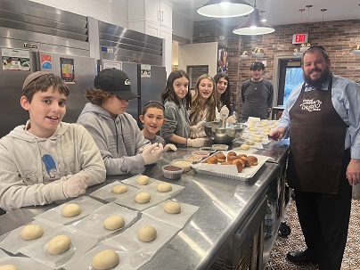 Chabad Hebrew School students learn to make donuts from scratch with Rabbi Pesach Burston. Donuts are traditionally eaten on Chanukah to commemorate the miracle of the oil