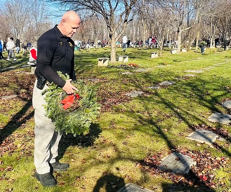 Sheriff Paul Arteta places a wreath on a grave at the Veterans Memorial Cemetery